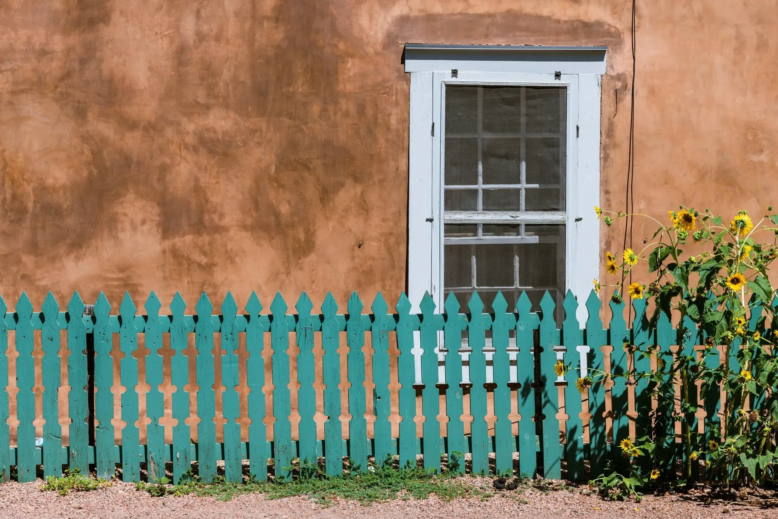 Exterior of adobe style home with blue fence, Santa Fe